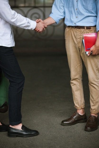 A close-up shot of a senior executive shaking hands with a junior colleague, emphasizing mentorship and knowledge transfer within a REIT management team.